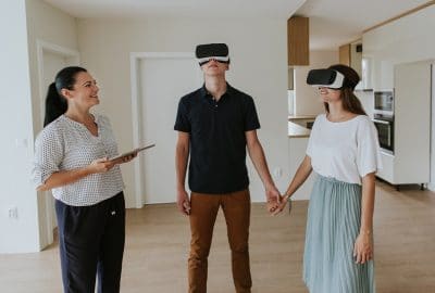 Estate agent with young couple wearing VR headsets in new apartment