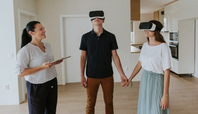 Estate agent with young couple wearing VR headsets in new apartment